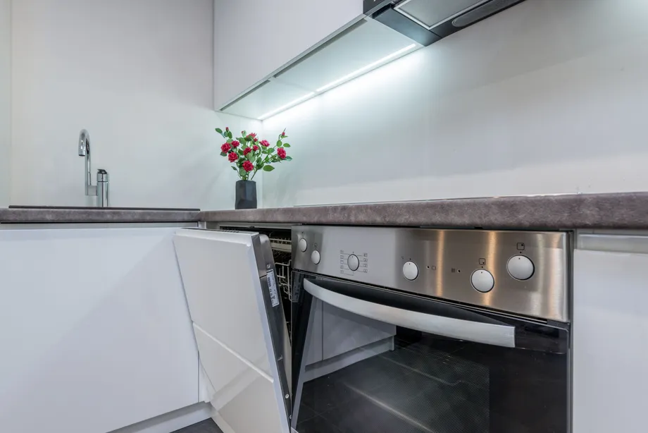 Open dishwasher beside a kitchen range